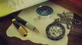 Pocket watch with old books and pen with paper map on the table by the window. Royalty Free Stock Photo