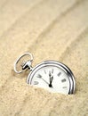 Pocket watch semi buried in the sand Royalty Free Stock Photo