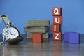 A pocket watch, stack of book and red wooden cube written with QUIZ on a table Royalty Free Stock Photo