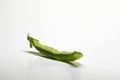 A pod of green peas on a white background.