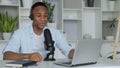 Podcast concept - happy young black man audio blogger in headphones with laptop computer and microphone broadcasting at Royalty Free Stock Photo