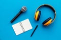 Podcast record with notebook, microphone and headphones on blue background top view space for text