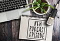 Podcast recording equipment on rustic wooden table with words new podcast episode written on note pad