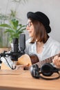 podcaster creates content, happy woman musician with guitar records podcast with microphone and headphones, Caucasian