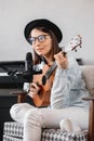 podcaster creates content, happy woman musician with guitar records podcast with microphone and headphones, Caucasian