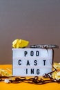 Podcasting lettering and audio cassette tape, headphones, crumpled paper in minimalistic isometric style. Trendy colors