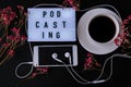 Podcasting lettering. Headphones mobile phone. Dry pink flowers decoration. Workplace. Black coffee