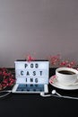 Podcasting lettering. Headphones mobile phone. Dry pink flowers decoration. Workplace. Black coffee