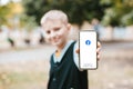 Podolsk, Ukraine - March 29, 2021: Close up photo of boy hand holds new smartphone with Facebook profile account page on