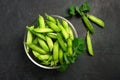 Pods of green peas in a bowl on a dark background. Food, diet, vegetarianism, vitamins. Flat lay