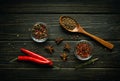 Pods of red chili peppers and dry spices with coriander in a spoon on a black vintage table prepared for adding to food. Free