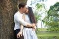 Pofile of a multicultural newlywed couple kissing next to a tree in a park Royalty Free Stock Photo