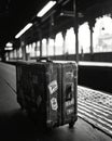 Black and white image of an old suitcase in a train station. Royalty Free Stock Photo