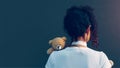 a women looking at a gloomy wall with a teddy bear at her back trying to cope with her mental illness