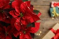 Poinsettia traditional Christmas flower and gifts on wooden table, top view. Space for text Royalty Free Stock Photo