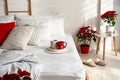 Poinsettias near bed in light cozy room. Christmas Interior design Royalty Free Stock Photo