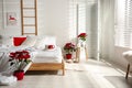 Poinsettias near bed in light cozy room. Christmas Interior design Royalty Free Stock Photo