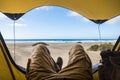 Point of view with laying man inside a tent enjoying relax and adventure in free camping with beach and sea blue sea and sky