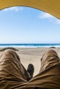 Point of view with laying man inside a tent enjoying relax and adventure in free camping with beach and sea blue sea and sky