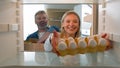 Point of view POV from inside refrigerator middle-aged couple spouses adult man and woman husband and wife taking Royalty Free Stock Photo