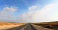 A point of view shot driving on a long straight road in desert grasslands at sunrise or sunset. A light plane flying in