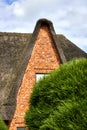Pointed high gable of a house with thatched roof behind a green bush, Sylt, Germany Royalty Free Stock Photo