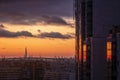 Pointed skyscraper silhouette, soft orange sunset sky and dark blue heavy clouds