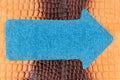 Pointer made of denim is lying on a brown crocodile skin, with space for your text.