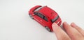 Pointing finger touches back of red small Fiat 500 toy