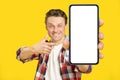 Pointing at giant, huge smartphone with white empty screen blond man, wearing red plaid shirt. Man with phone display Royalty Free Stock Photo