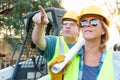 Pointing Male and Female Workers With Technical Blueprints Talking Royalty Free Stock Photo