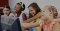 Pointing and smiling four female students using computers in school lab, with keyboards and mice Royalty Free Stock Photo