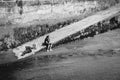 A woman waits on a pier next to an outboard motor.