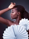 Poised with beauty and elegance. Studio shot of a beautiful young woman posing with origami fans against a black