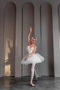 Poised young ballerina with feathered tiara, classic white tutu, stands on tiptoes in pointe