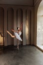 Poised young ballerina with feathered tiara, classic white tutu, stands on tiptoes in pointe