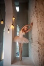 Poised young ballerina in white tutu, feather tiara performs on urban stage, expression serene