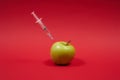 Poison enters the green apple with a syringe. Royalty Free Stock Photo