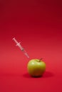 Poison enters the green apple with a syringe. Royalty Free Stock Photo