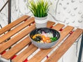 Poke bowl with avocado, radish, salmon, corn, seaweed, peas, nori, daikon, sesame seeds in black plate Royalty Free Stock Photo