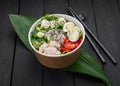 Poke bowl with chicken, rice, avocado, cucumber, cream cheese, tomato and quail egg on dark background Royalty Free Stock Photo