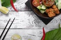 Poke bowl with fried chicken, vegetables and rice on the white wooden table. Hawaiian cuisine meal