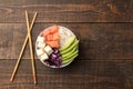 Poke bowl Hawaiian food. plate of rice, salmon, avocado, cabbage and cheese, on a brown wooden table. top view