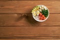 poke bowl with salmon, avocado, rice, Chuka Salad, cheese,, quail eggs sprinkled with white and black sesame isolated on wooden