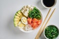 poke bowl with salmon, avocado rice, Chuka Salad,sweet onions, quail eggs sprinkled with white and black sesame with chopsticks,