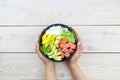 Poke bowl of salmon, rice, avocado, cucumber, mango, herbs in a woman's hands. Hawaiian ahi, a diet meal with fish Royalty Free Stock Photo