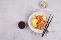 Poke bowl with salmon, rice, avocado, sesame seeds, micro greens,persimmon, black and white sesame seeds and soy sauce. Royalty Free Stock Photo