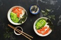 Poke bowl with salmon rice and vegetables on a dark stone background. Traditional Hawaiian raw fish salad. Top view, flat lay Royalty Free Stock Photo