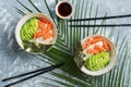 Poke bowl with salmon rice and vegetables on grey background with palm leaves. Traditional Hawaiian raw fish salad. View from Royalty Free Stock Photo