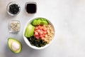 Poke bowl served with salmon, avocado, cucumber, quinoa, wakame seaweed on gray background with ingredients Royalty Free Stock Photo